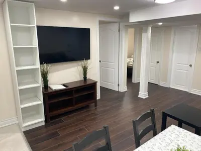 a living room with a television and a table and chairs at Adorable private 2 bedroom basement unit in Toronto