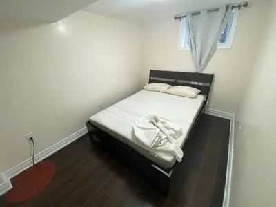 a small bedroom with a bed with white sheets and pillows at Adorable private 2 bedroom basement unit in Toronto