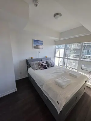 a bedroom with a large bed with a large window at Amazing one bedroom suite with panoramic downtown views in Toronto