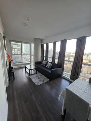 a living room with a couch and large windows at Amazing one bedroom suite with panoramic downtown views in Toronto