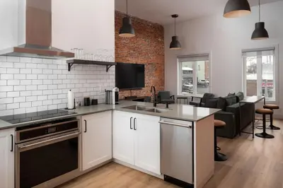 a kitchen with white cabinets and a brick wall at Beam Loft in Beamsville