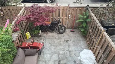 a motorcycle parked in a backyard with a fence at Picturesque 3-story townhouse in Toronto
