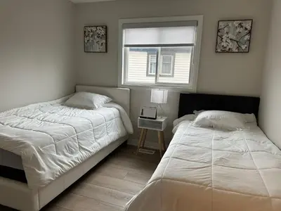 two twin beds in a bedroom with a window at K Niagara Guesthouse in Niagara Falls
