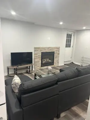 a living room with a black couch and a fireplace at New 2 bedroom basement in Cambridge in Cambridge