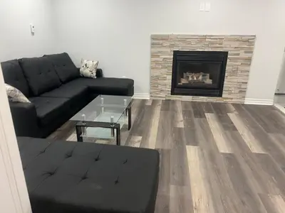 a living room with a black couch and a fireplace at New 2 bedroom basement in Cambridge in Cambridge