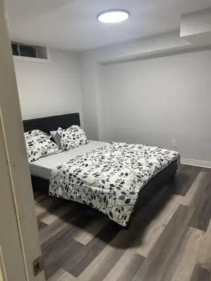 a bedroom with a bed with black and white sheets at New 2 bedroom basement in Cambridge in Cambridge