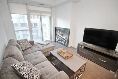 a living room with a couch and a flat screen tv at The Grand Avenue Suites - Downtown Toronto Entertainment District in Toronto