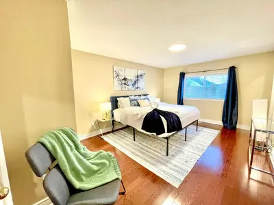a bedroom with a bed and a chair and a window at Maison Laurier, Modern 5B4B Home Inc BSMT Free parking, Close to trails in Richmond Hill