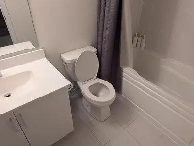 a white bathroom with a toilet and a sink at Sunshine room on Downsview in Toronto
