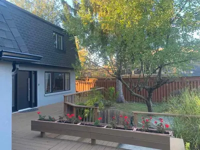 a backyard with a wooden deck with flowers and a tree at 3 BDR lake Simcoe cottage-free parking -day pass to provincial park-one hour from Toronto in Georgina
