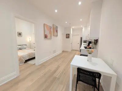 a white room with a bed and a white table at Luxury 1BR plus den walkout basement in Toronto