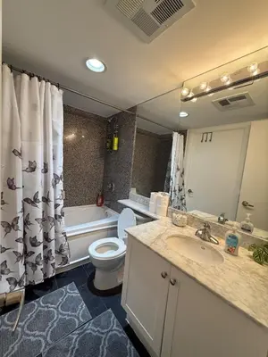 a bathroom with a sink and a toilet and a mirror at Cozy & Elegant Condo-Lake & City View-35th floor in Toronto