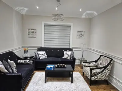 a living room with a black couch and a chair at Ensuite in New Home with Parking, Close to Bluffers Park, Lake Ontario, 15 Mins to Downtown in Toronto