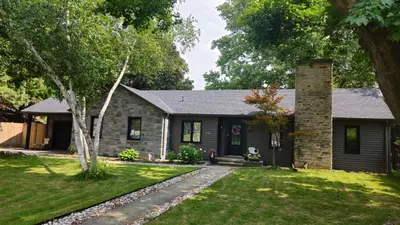 a stone house with a brick chimney and a yard at Forest city family style furnished rooms in London