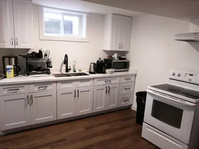 a kitchen with white cabinets and a white stove top oven at Forest city family style furnished rooms in London