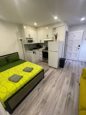 a bedroom with a yellow bed and a kitchen at Toronto Downtown Holiday Home-Private Patio,Free Wifi & Self Checkin in Toronto