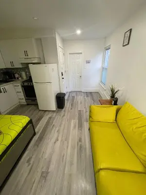 a living room with a yellow couch and a kitchen at Toronto Downtown Holiday Home-Private Patio,Free Wifi & Self Checkin in Toronto
