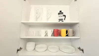 a cupboard filled with white plates and mugs at Nordic Three Brantford in Brantford