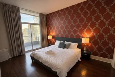 a bedroom with a large bed with a red wall at Luxury Penthouse with Celebration Square Views in Mississauga