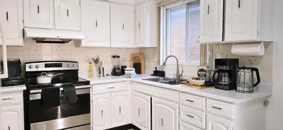 a kitchen with white cabinets and a black stove top oven at Luxury 3BR Near Pearson Airport Free Parking in Toronto