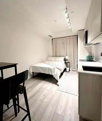 a white bedroom with a bed and a kitchen at Cozy studio near Yonge Eglinton Subway Midtown in Toronto