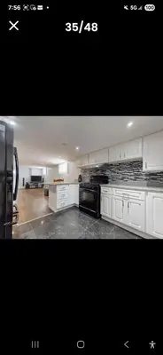 a kitchen with white cabinets and a black appliances at Cozy home in Toronto