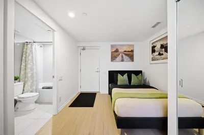 a white bedroom with a bed and a toilet at Spacious Condo with 2 Beds Unbeatable Location in Toronto