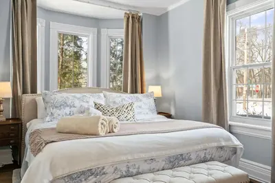a bedroom with a bed with blue walls and windows at Modern French Cottage in Old Town The 506 in Niagara on the Lake