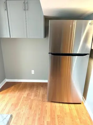 a stainless steel refrigerator in a kitchen with wooden floors at Beautiful walkout basement in Georgetown