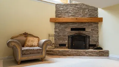 a living room with a stone fireplace and a chair at Muskoka 4-Bedroom Cottage in Port Carling