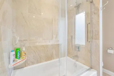 a bathroom with a tub and a shower with a glass door at Beautiful 3BR Old Town Home Steps to Queen St in Niagara on the Lake