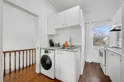 a white kitchen with a washing machine and a sink at 1 Bed Suite Steps to Bloor in Toronto