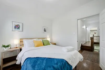 a bedroom with a large bed with white walls at 1 Bed Suite Steps to Bloor in Toronto