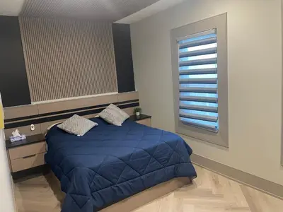 a bedroom with a blue bed and a window at Modern 4 Bedroom Ground Floor Bungalow Style Home in Niagara Falls