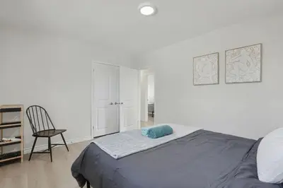 a white bedroom with a bed and a chair at New 3BR Home - Minutes to the Falls in Niagara Falls