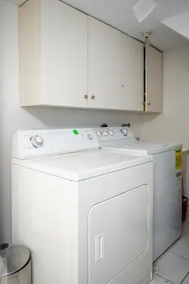 a white washer and dryer in a kitchen with white cabinets at Basement Suite for 2 w Private Patio in Toronto in Toronto