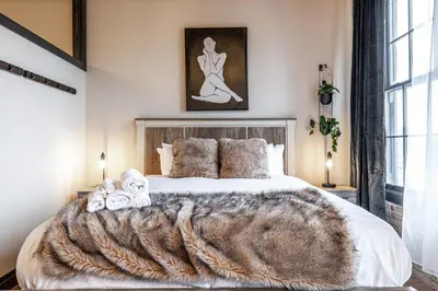 a bedroom with a large bed with a fur blanket at Bradshaw Lofts The Brixton King Suite in Stratford
