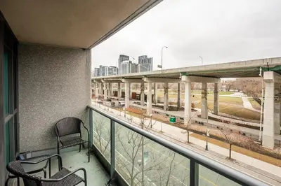 a balcony with two chairs and a view of a highway at Modern 1Bedroom Condo with Balcony Downtown Toronto in Toronto