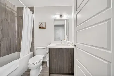 a white bathroom with a toilet and a sink at Your Friday Harbour Escape Awaits! in Innisfil