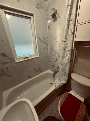 a bathroom with a toilet and a tub and a window at Space Share Accommodation East York Budget Friendly in Toronto