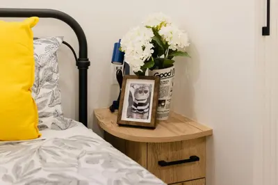 a side table with a vase of flowers and a picture at Central Getaway University of Toronto TTC Queen M in Toronto