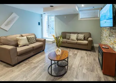 a living room with two couches and a table at Modern Cozy Executive Suite with Private Entrance in London