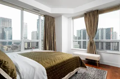 a bedroom with a large bed and large windows at Comfort and Beauty in the heart of Tor | W Parking in Toronto