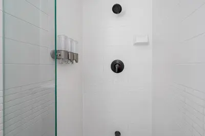 a shower with a glass door and white tiles at Comfort and Beauty in the heart of Tor | W Parking in Toronto