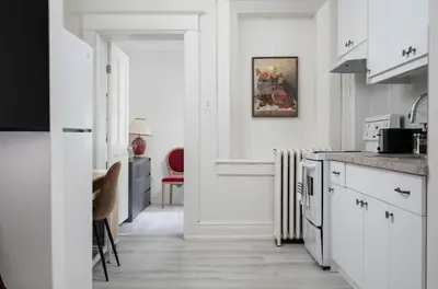 a kitchen with white cabinets and a red chair at Stylish Roncesvalles Flat in Toronto