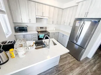 a kitchen with a stainless steel refrigerator and white cabinets at Quiet Haven in Oshawa