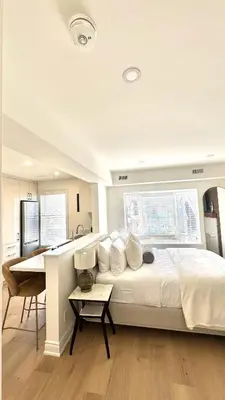 a bedroom with a bed and a desk and a kitchen at Bright & Cozy Private Studio Apartment in Toronto