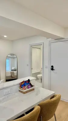 a white room with a table with chairs and a mirror at Bright & Cozy Private Studio Apartment in Toronto