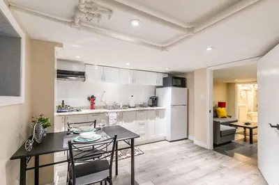 a kitchen with white cabinets and a table and chairs at Cozy Suite Condo - Heart Of St Clair West - Bloor Hotel in Toronto