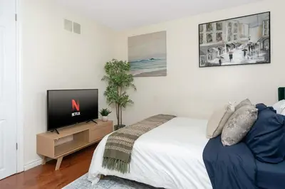 a bedroom with a large bed and a television at House with 5 Beds for Families in Great Location in Mississauga